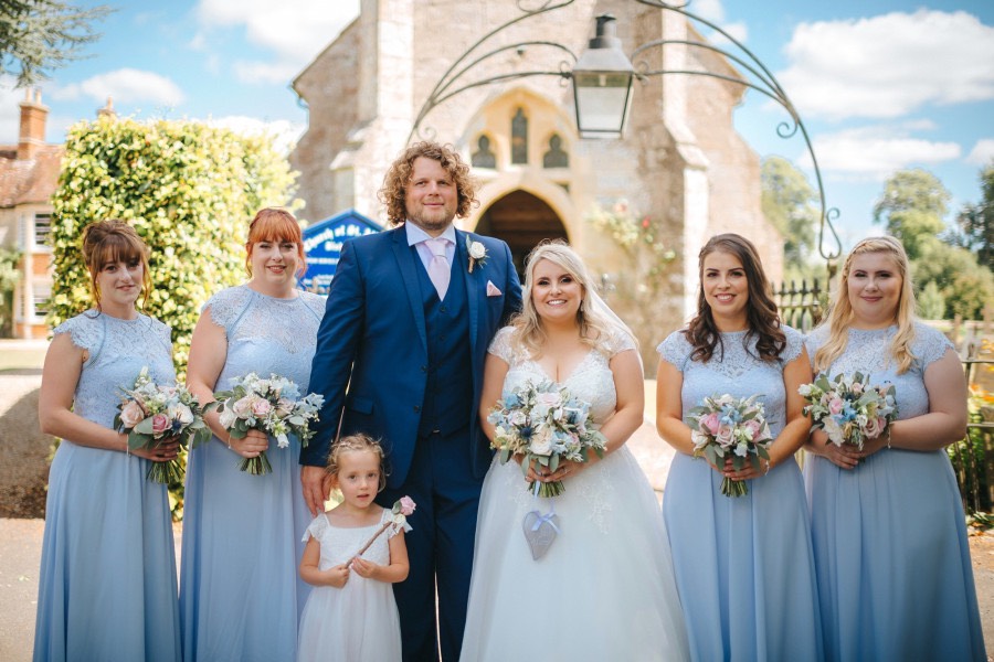 bride and groom with bridesmaids and flower girl in pale blue and ivory