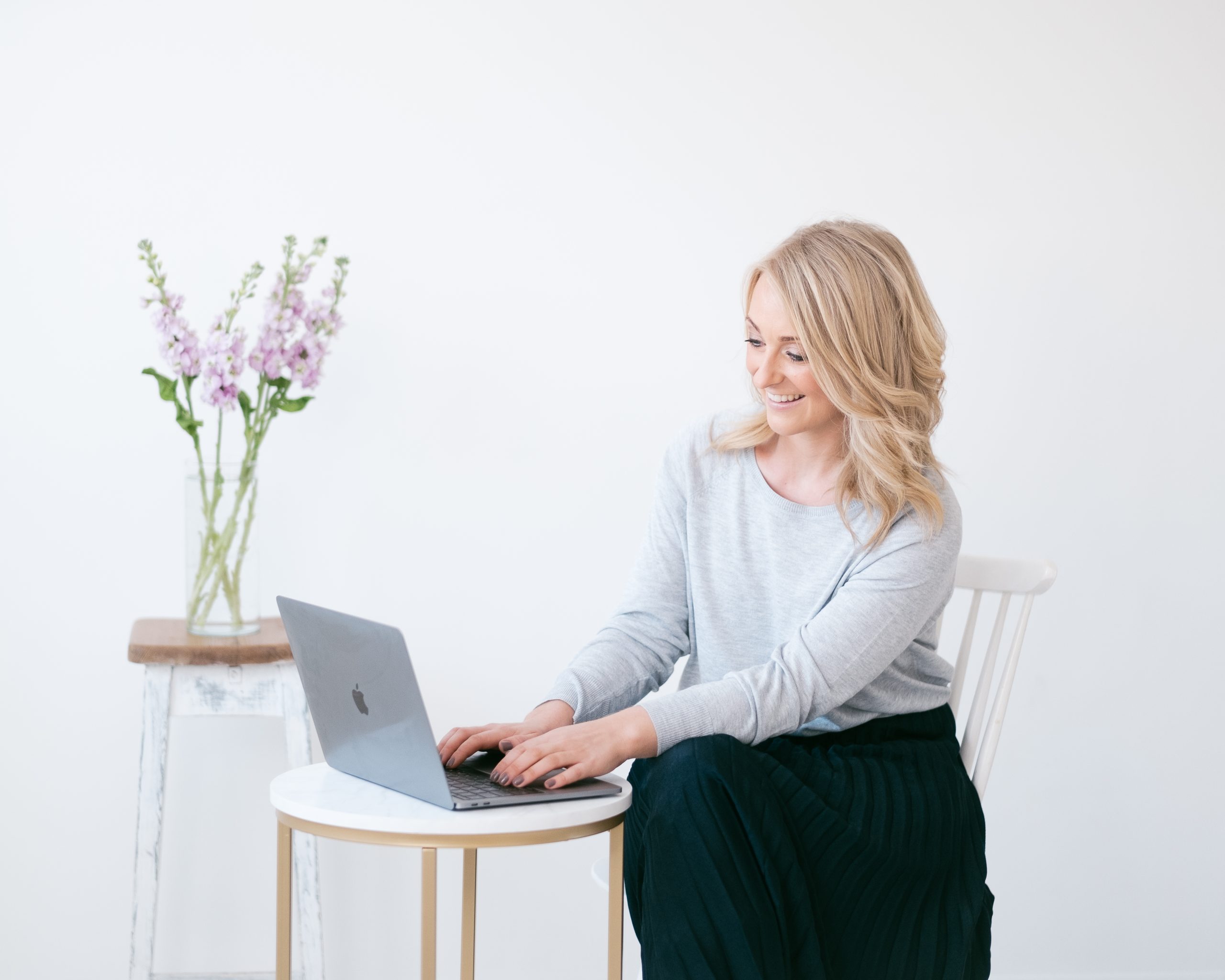 Emily Daisy Lane Floral Design working at laptop beside vase of flowers