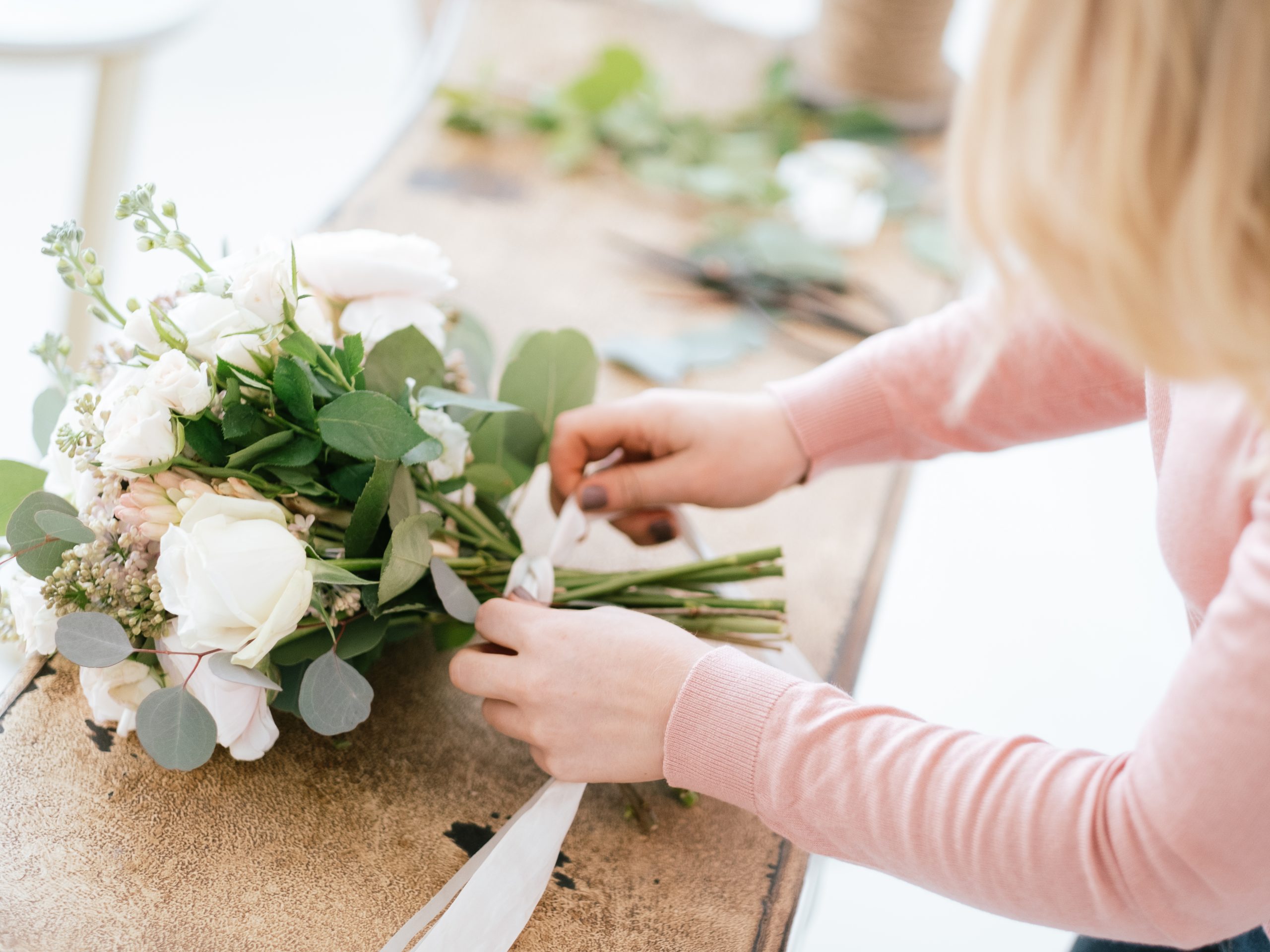 Daisy lane floral design florist tying ribbon around wedding bouquet