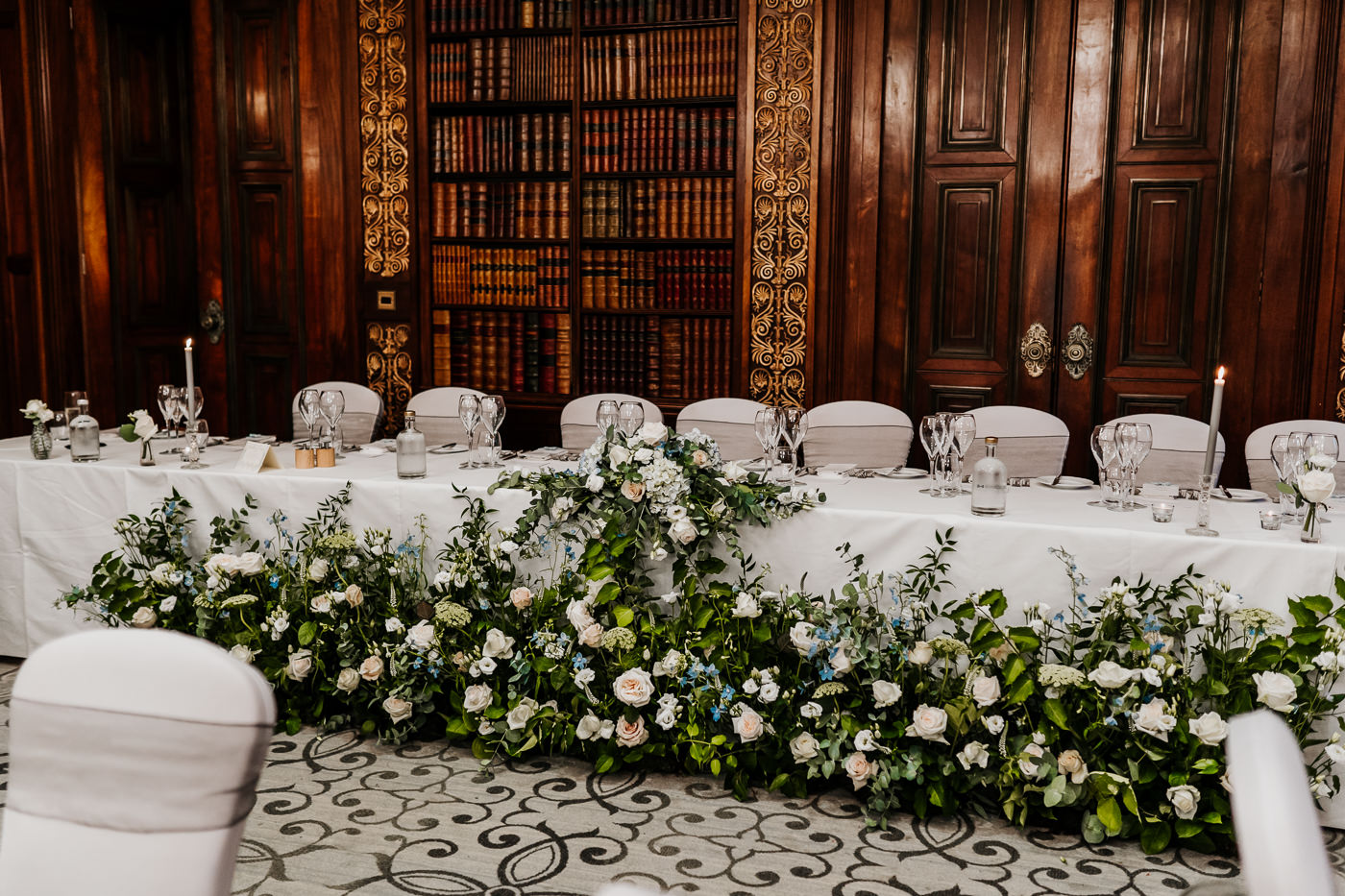 Daisy Lane Floral Design meadow arrangements in front of top table at wedding breakfast Clevedon Hall