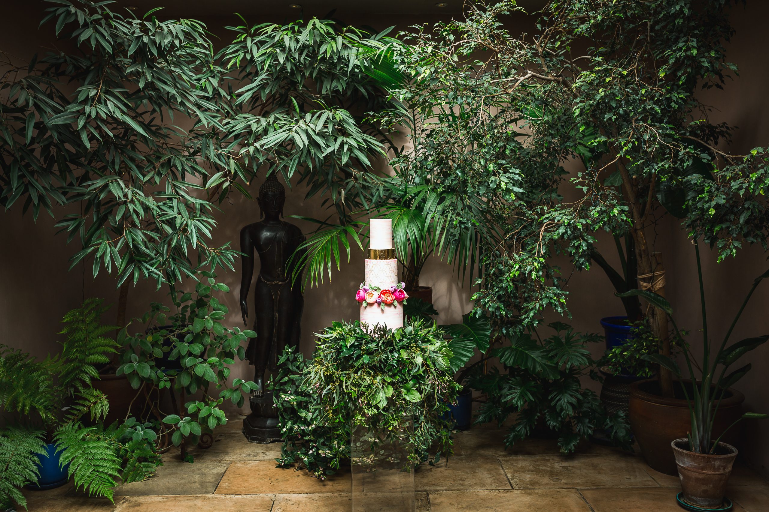 wedding cake on table surrounded by foliage