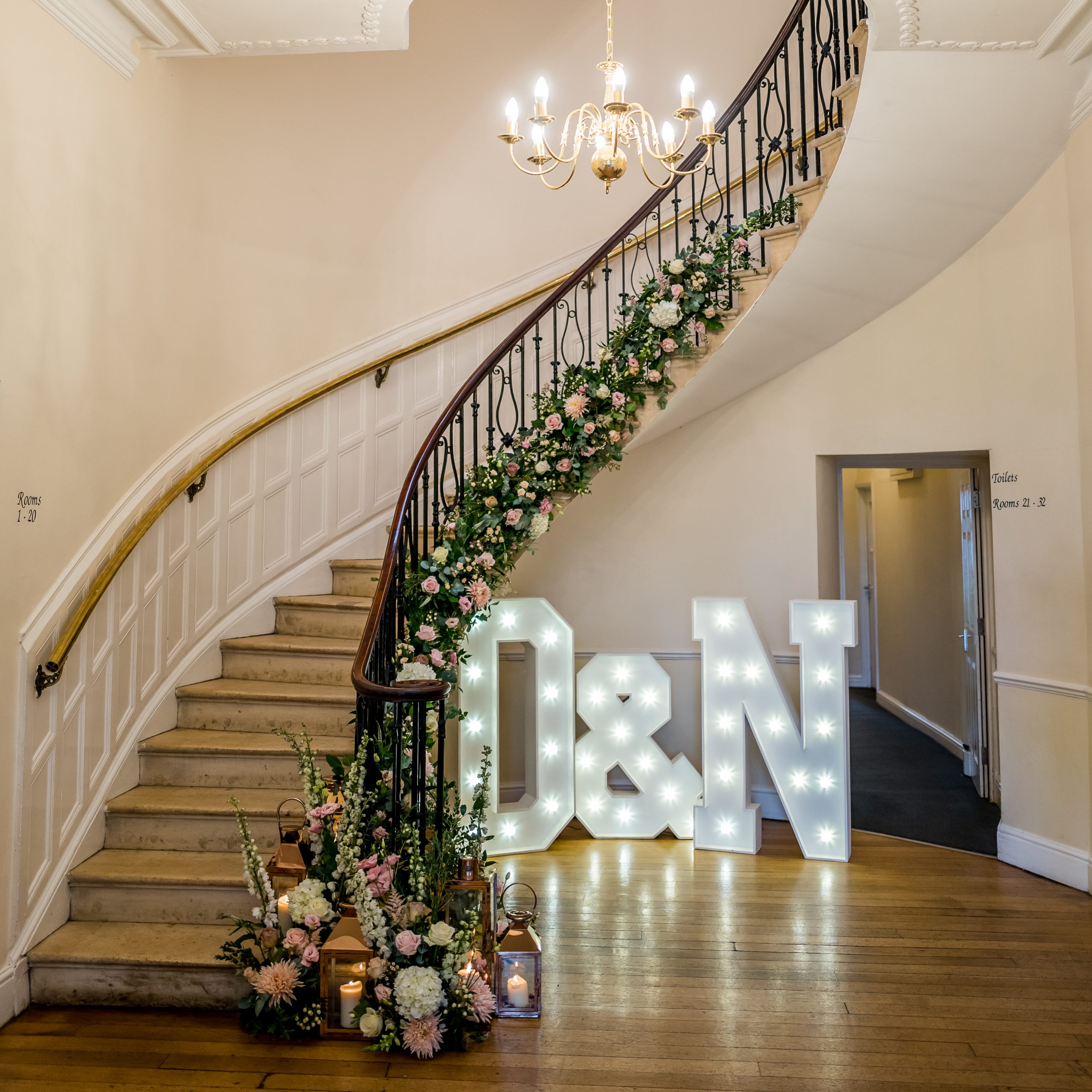 wedding flowers at eastington park staircase decorated with flowers large light-up letters